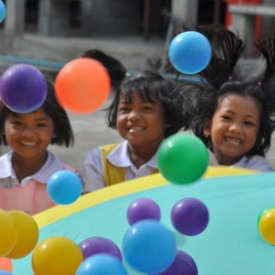 Children outside a kindergarten in Thailand play with colourful balls during a physical activity led by Projects Abroad Childcare volunteers. Projects Abroad volunteers in Thailand do outdoor activities with children at a kindergarten in Thailand.